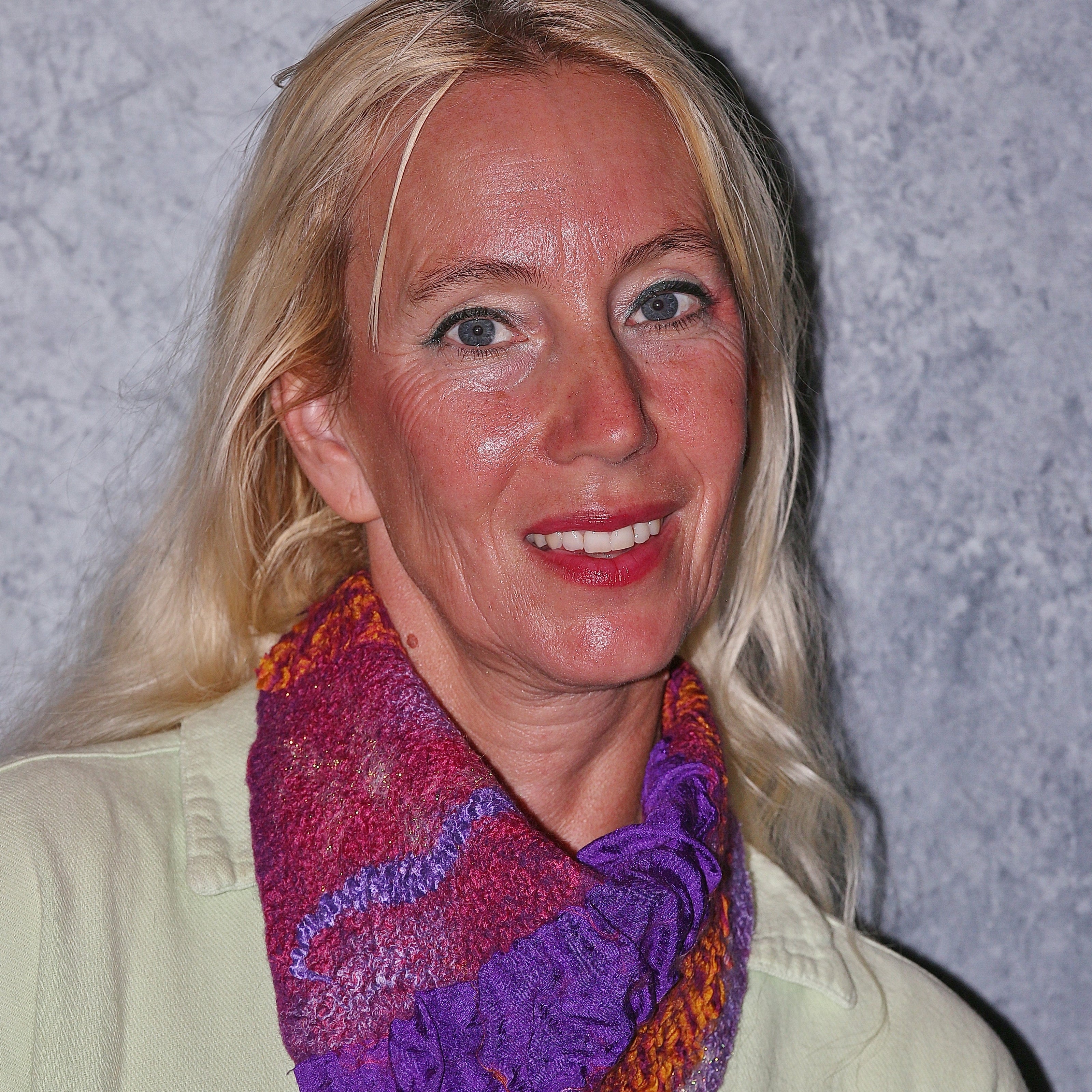 Woman wearing a colorful felted scarf against a plain background