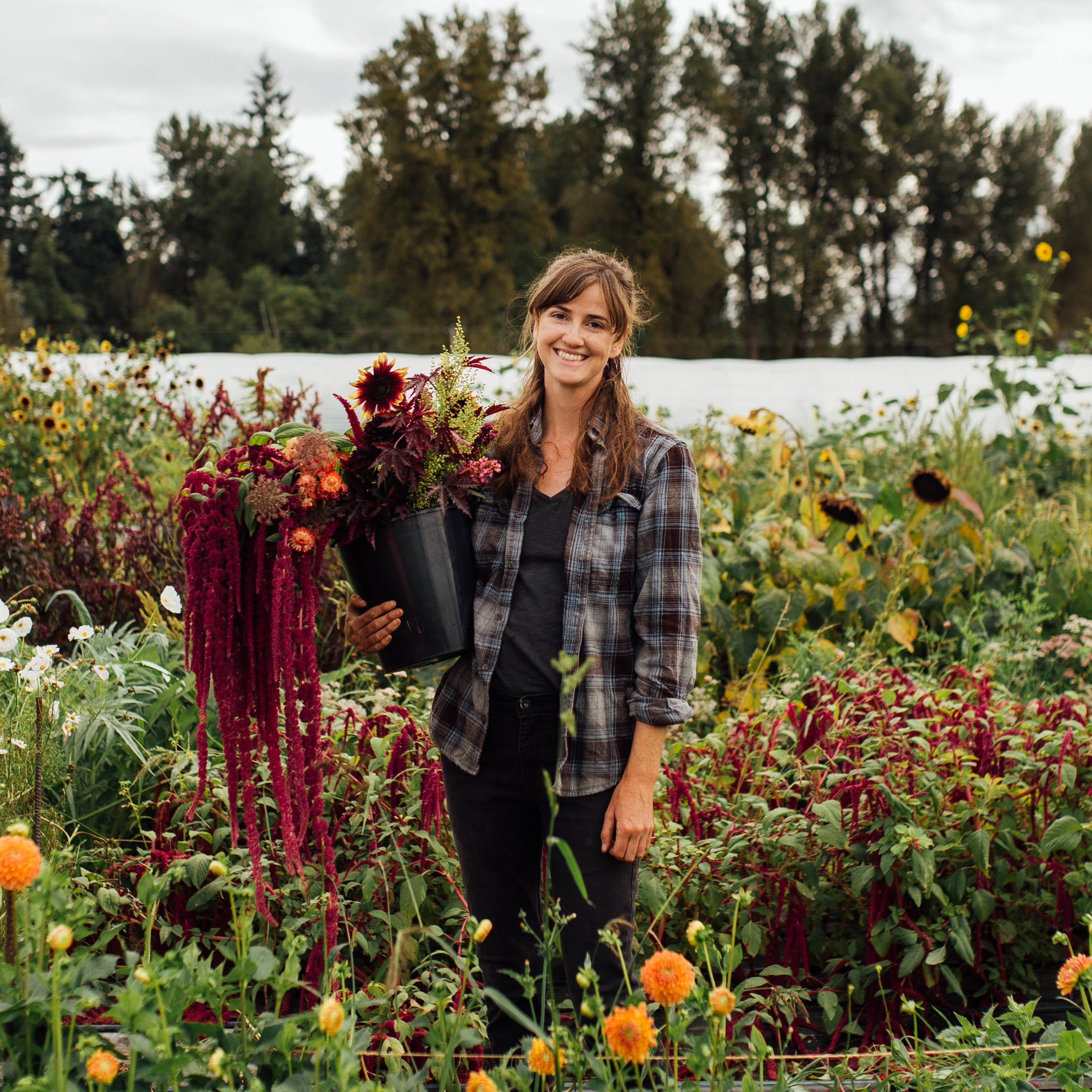 Person standing in a garden with various plants and flowers