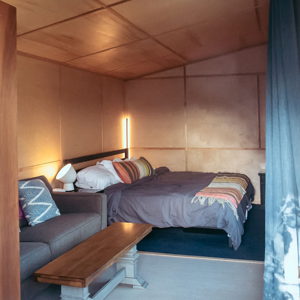 Small bedroom with a bed, sofa, and bench against wooden walls.